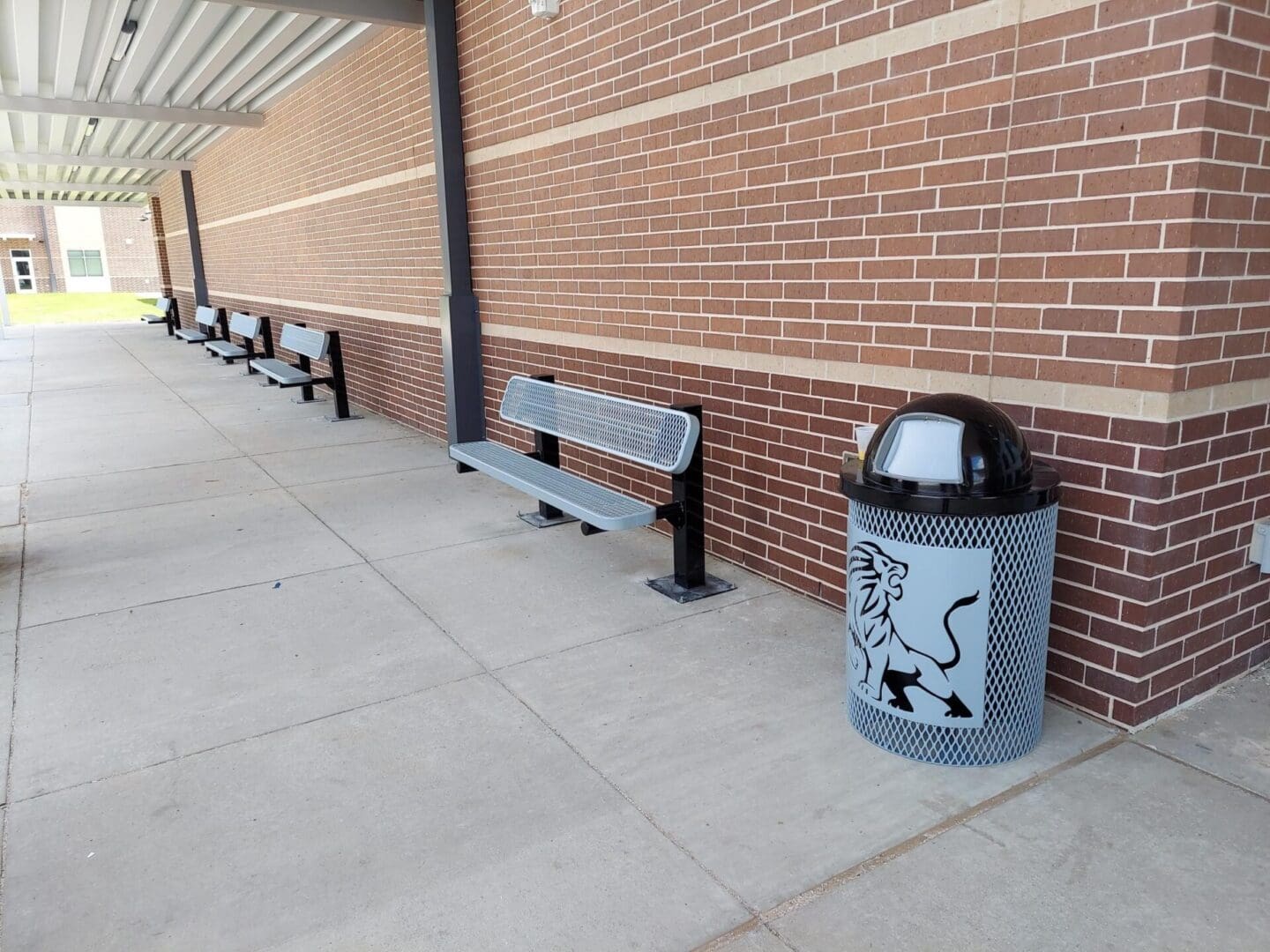 A bench and trash can are on the sidewalk.