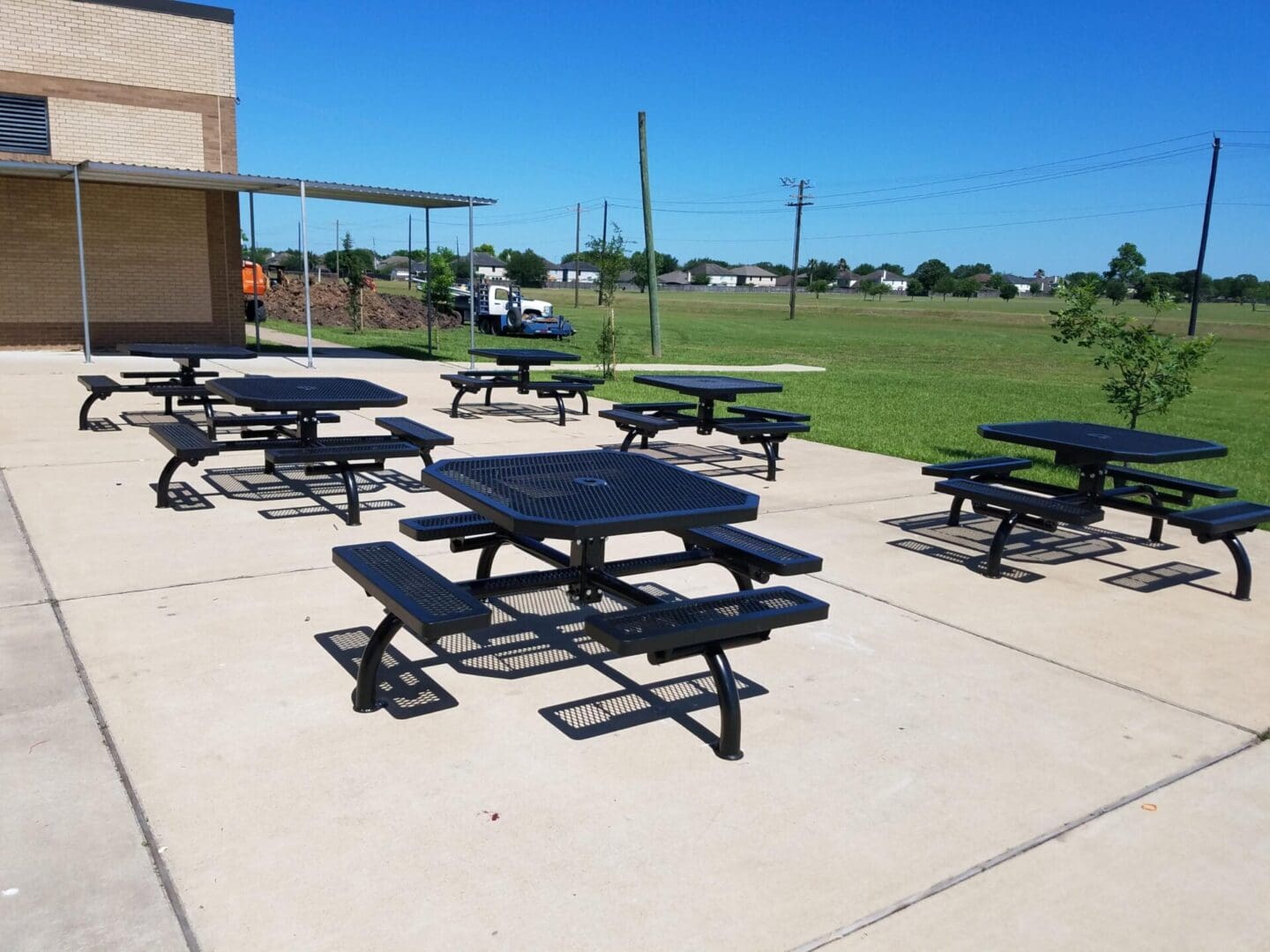A group of picnic tables sitting on top of cement.