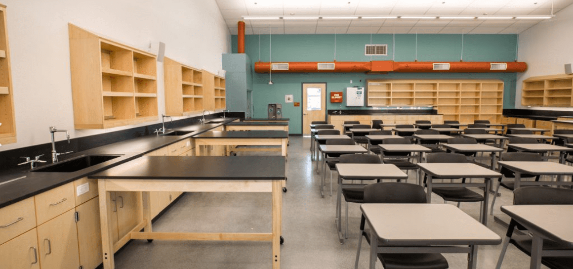 A classroom with desks and shelves in it