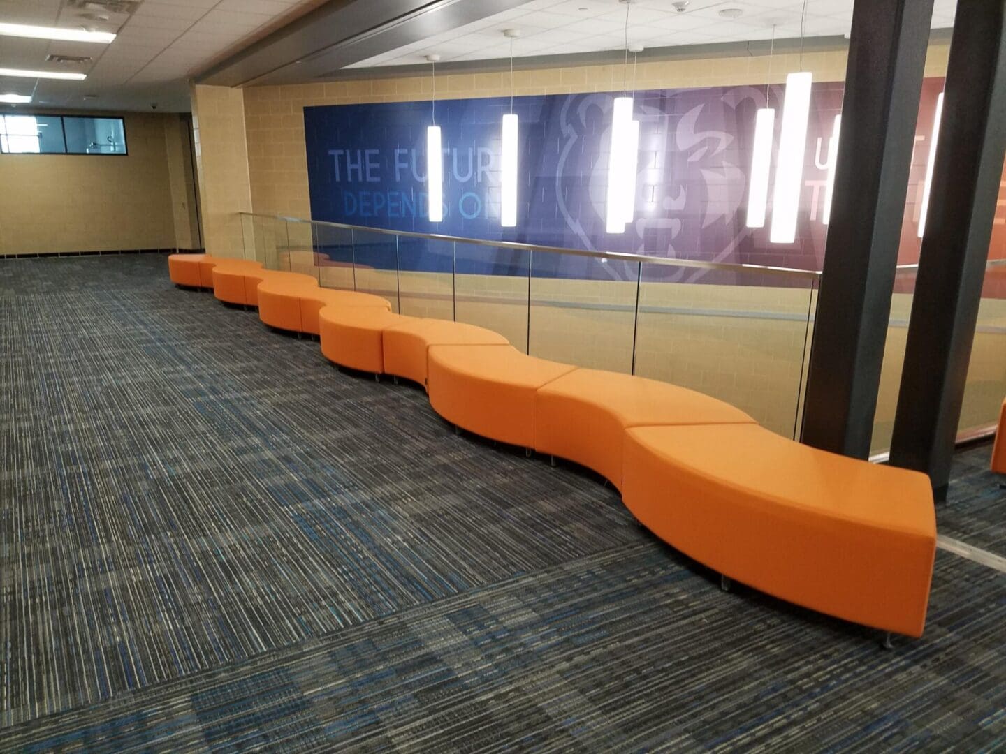 A row of orange benches in front of a wall.