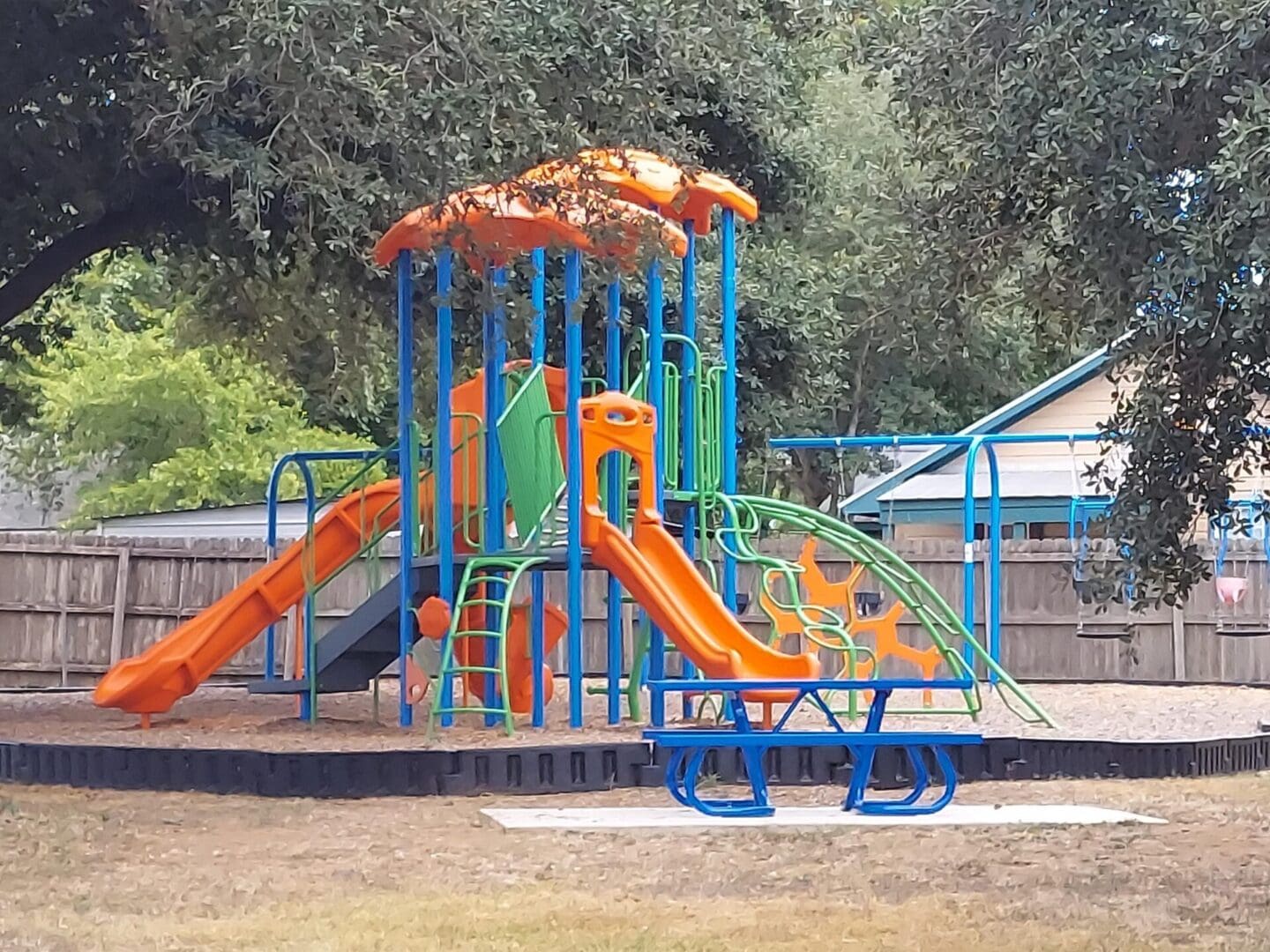 A playground with slides and swings in the middle of a park.