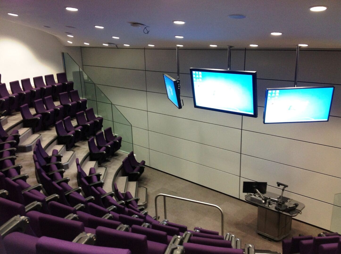 A large room with purple chairs and two big screens