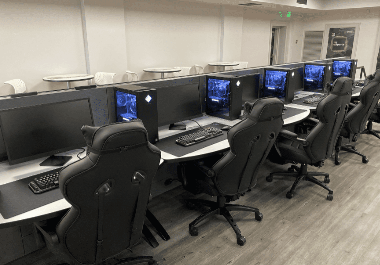 A long table with several computers on it.