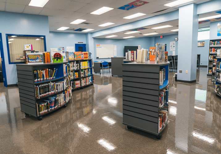 A library with several shelves of books and a book cart.