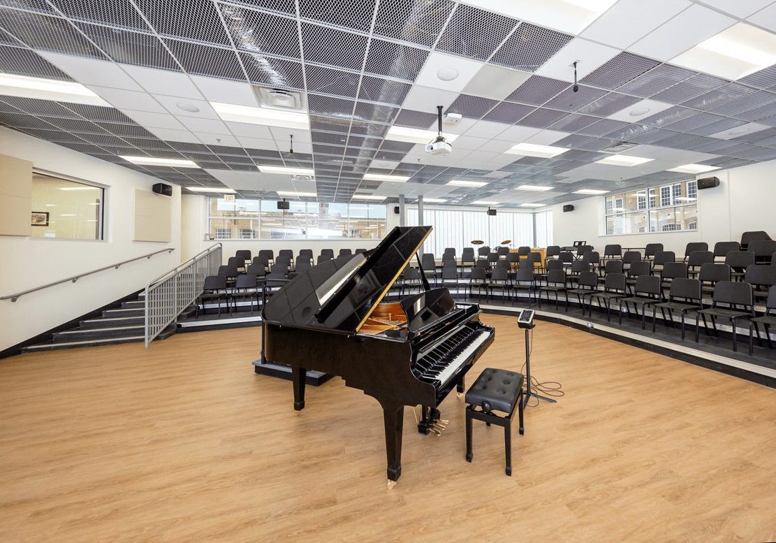 A piano in front of an auditorium with rows of seats.