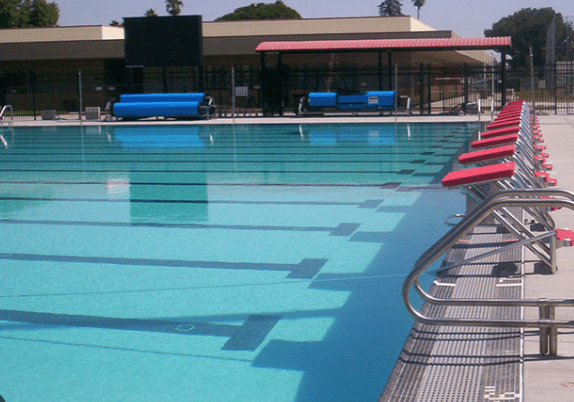 A swimming pool with blue water and red seats.