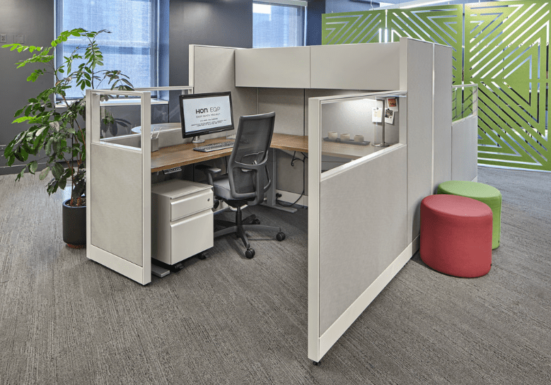 A cubicle with two desks and a chair.
