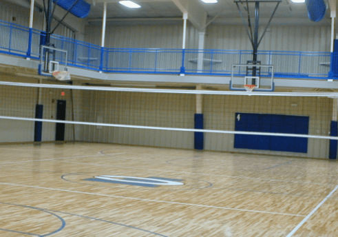 A gym with a basketball court and bleachers.