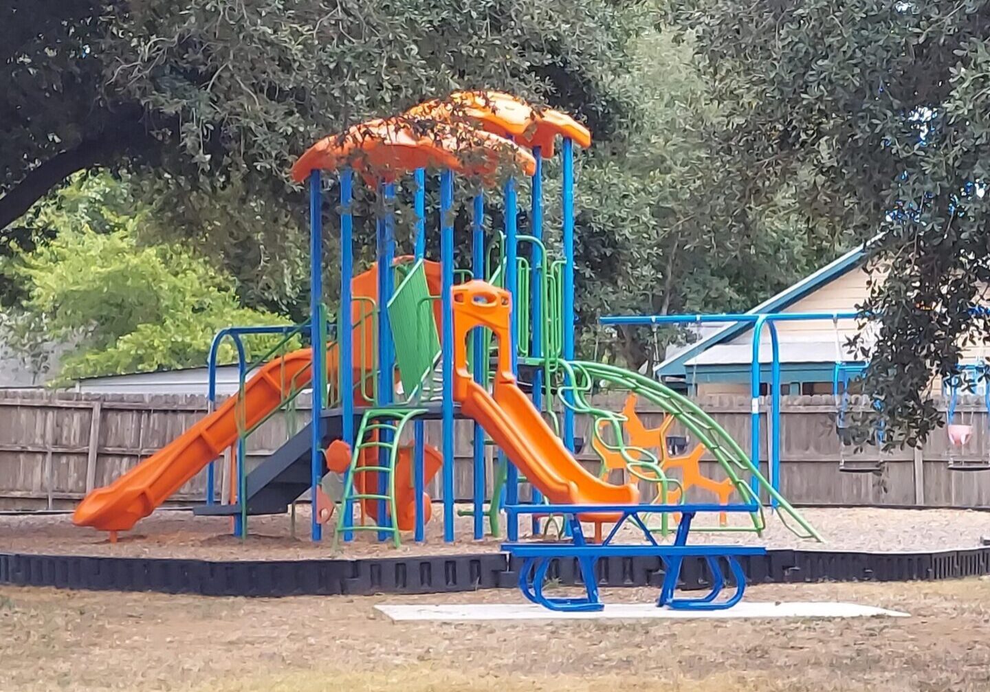 A playground with slides and swings in the middle of a park.