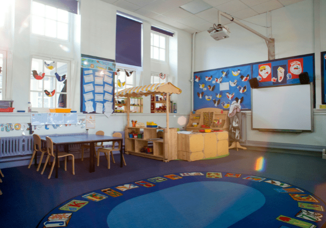 A classroom with tables, chairs and desks.